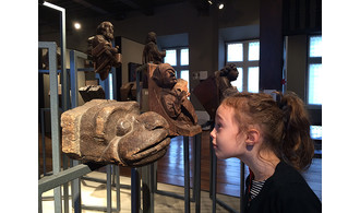 Enfant observant une tête sculptée de serpent